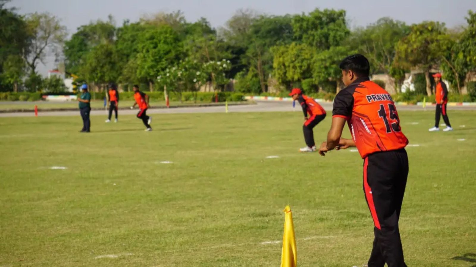About 9 Tisa students playing an inter-house cricket match on a lush green field, demonstrating the sports spirit of the best school in agra.