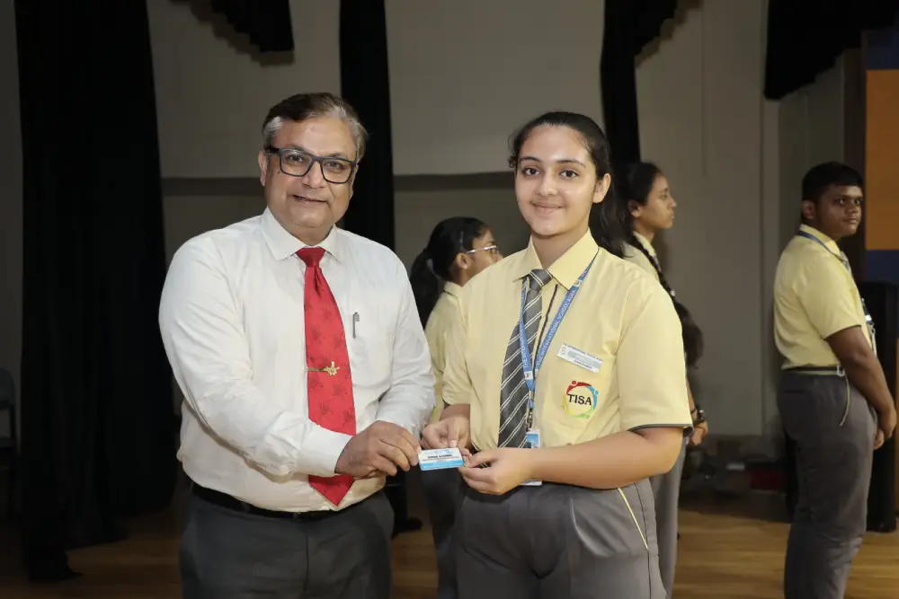 How does tisa support students academically from class ix to xii 1 School administrator presenting a badge to a student during a ceremony at tisa international school, agra.