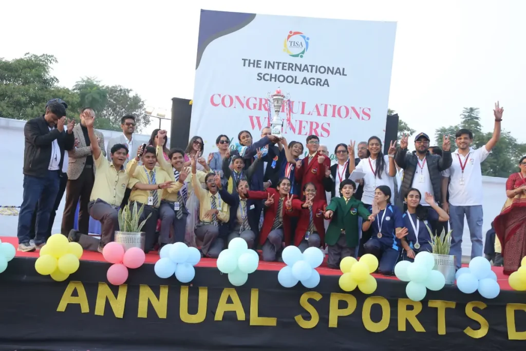 Co-curriculars in agra: choosing the right activities for students 3 Tisa students and staff celebrating with the championship trophy on annual sports day stage.